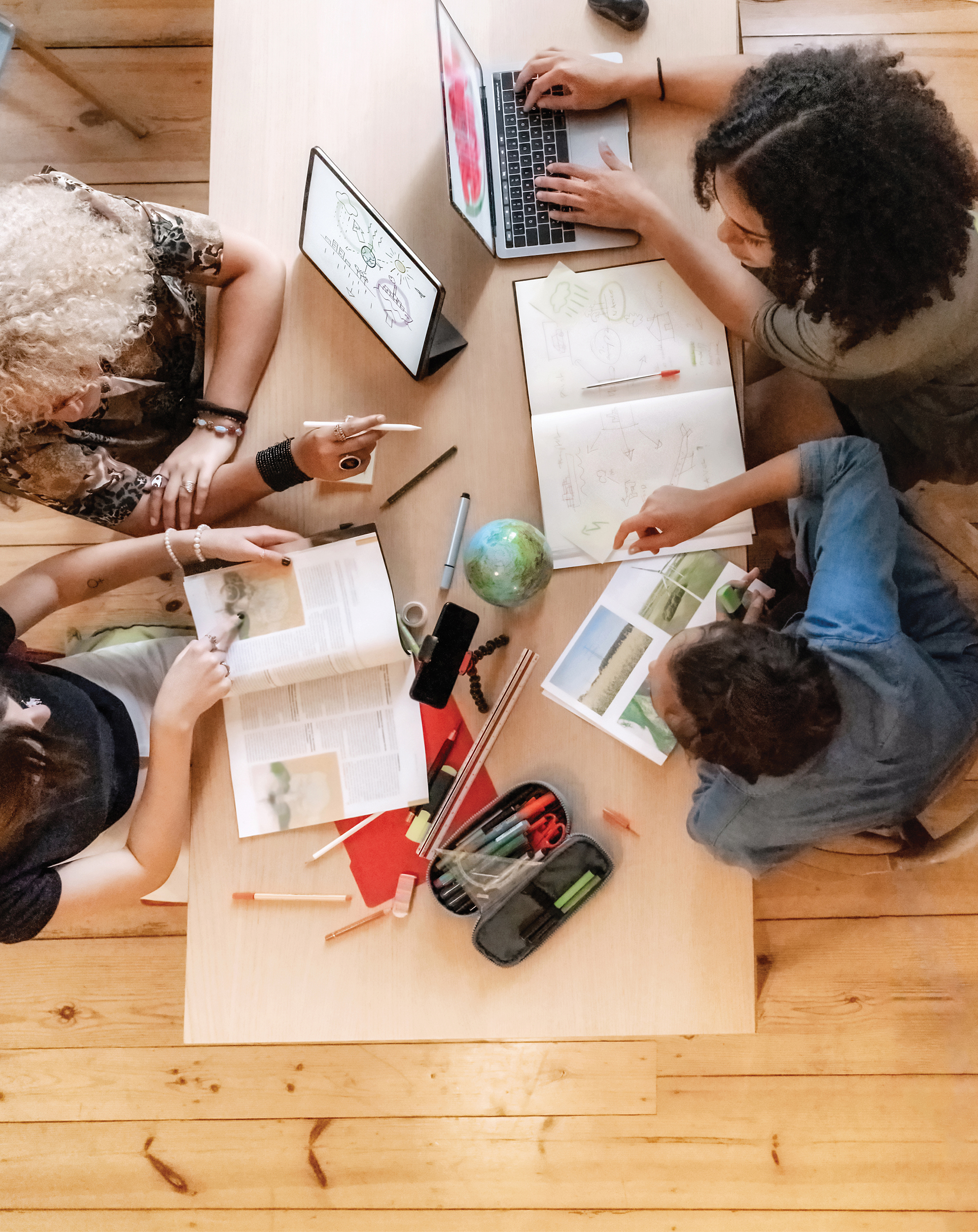 An overhead photo of four people sitting at a table working on a project together.