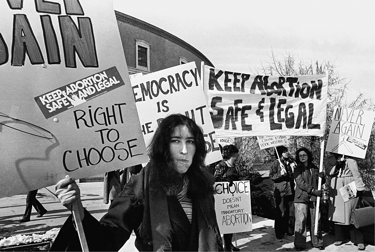 A black and white photo shows a group of women protesting in support of legal abortion.