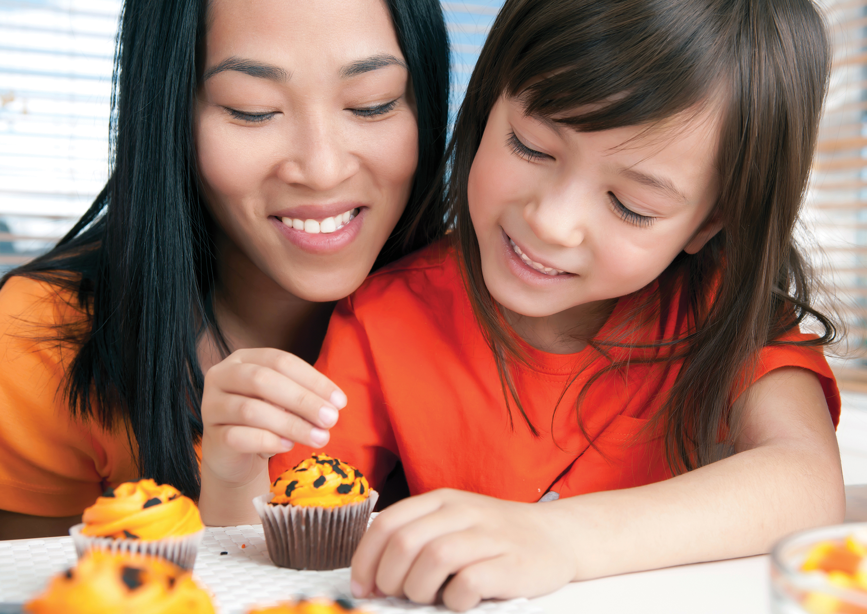 A photo shows a mother and daughter decorating a cupcake.