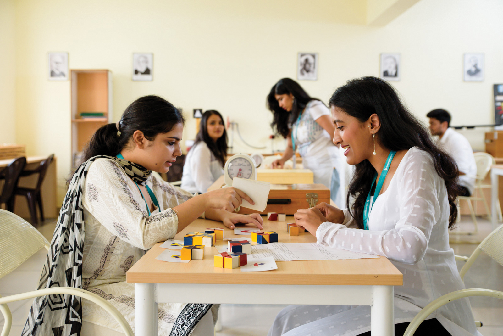 A photograph shows a researcher seated across from and observing a participant completing a puzzle at a table.