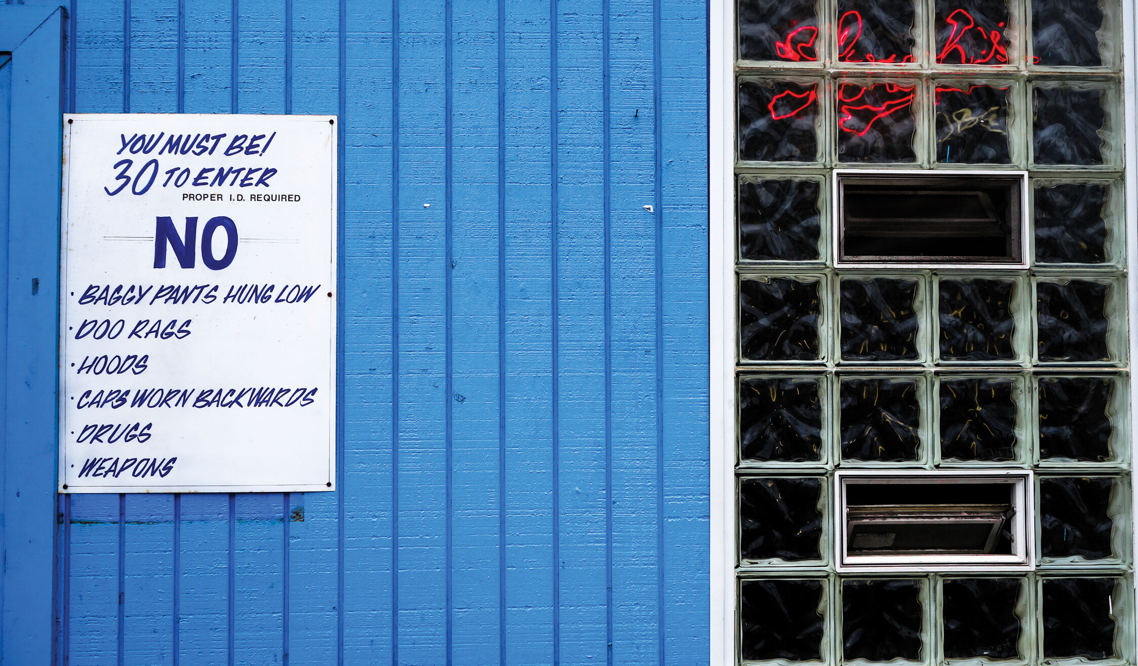 A sign hanging outside an establishment indicates the requirements and the rules to enter it.