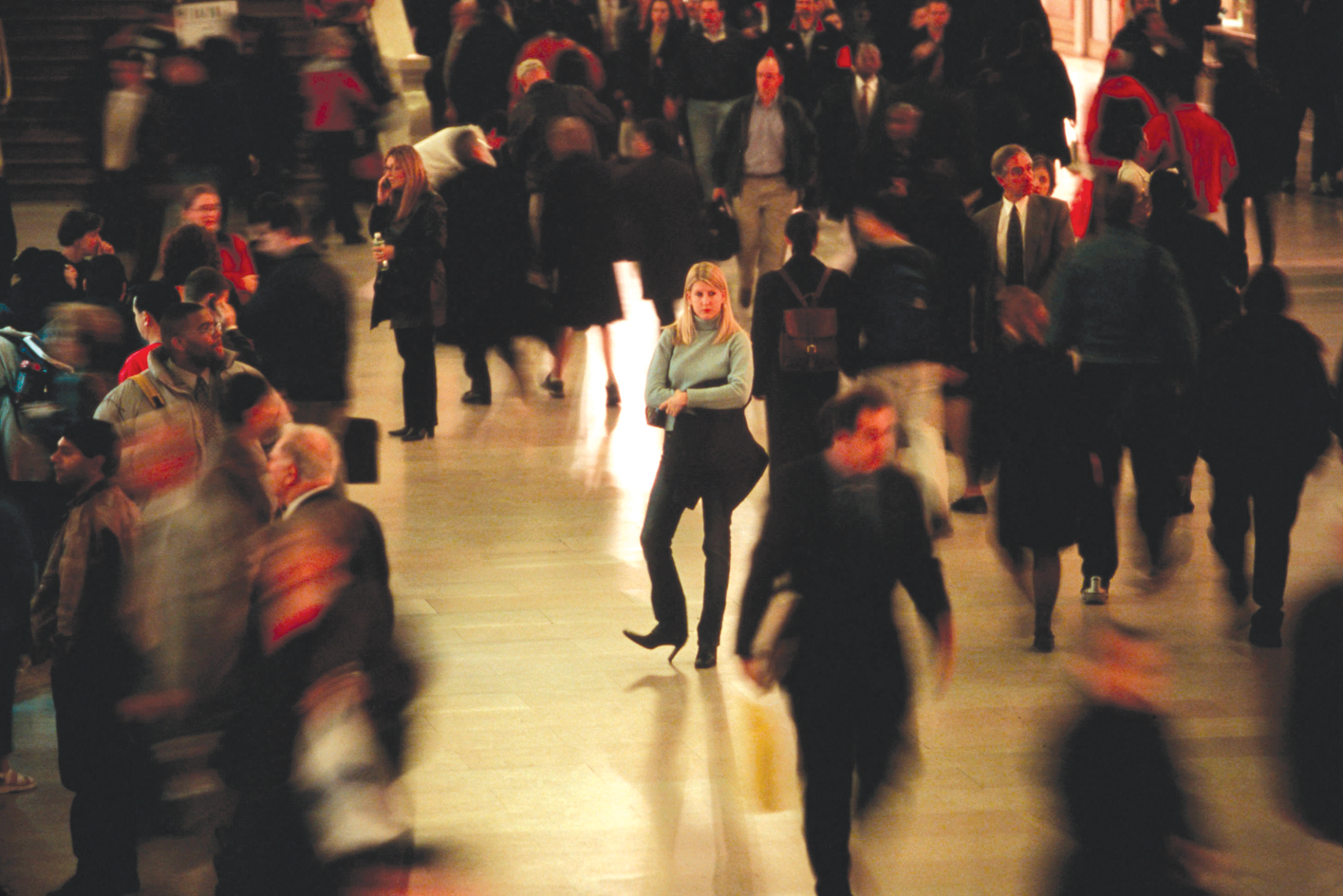 A woman standing in the center of a crowded place.