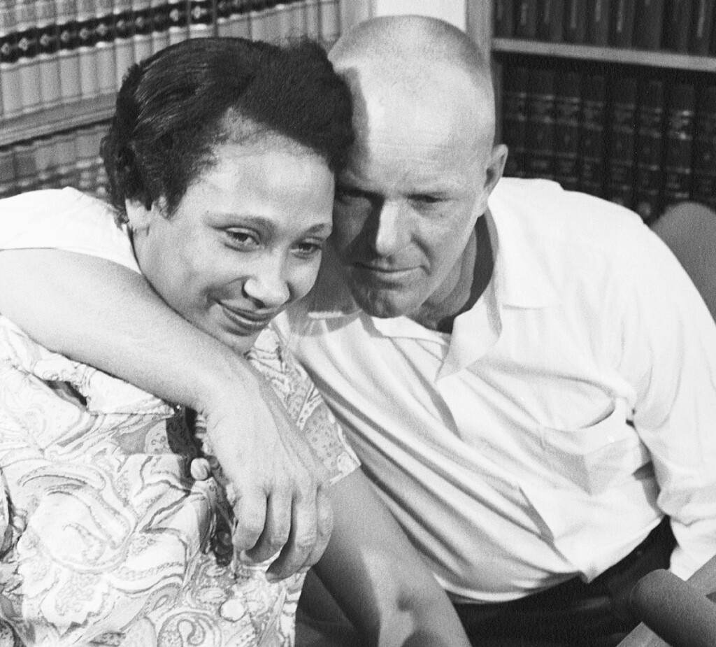 A black and white photo of a Black woman and a white man sitting surrounded by books.