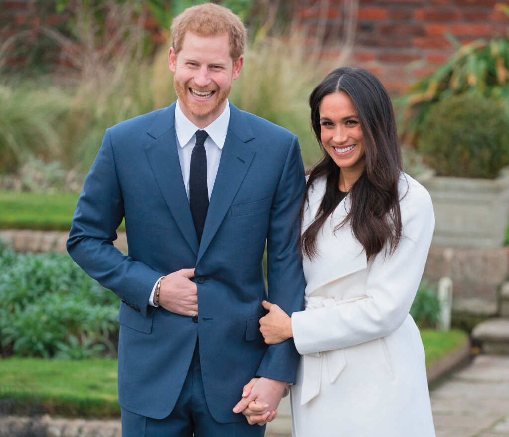 A photo of a bearded, red-haired white man and a smiling multi-racial woman standing in a garden.