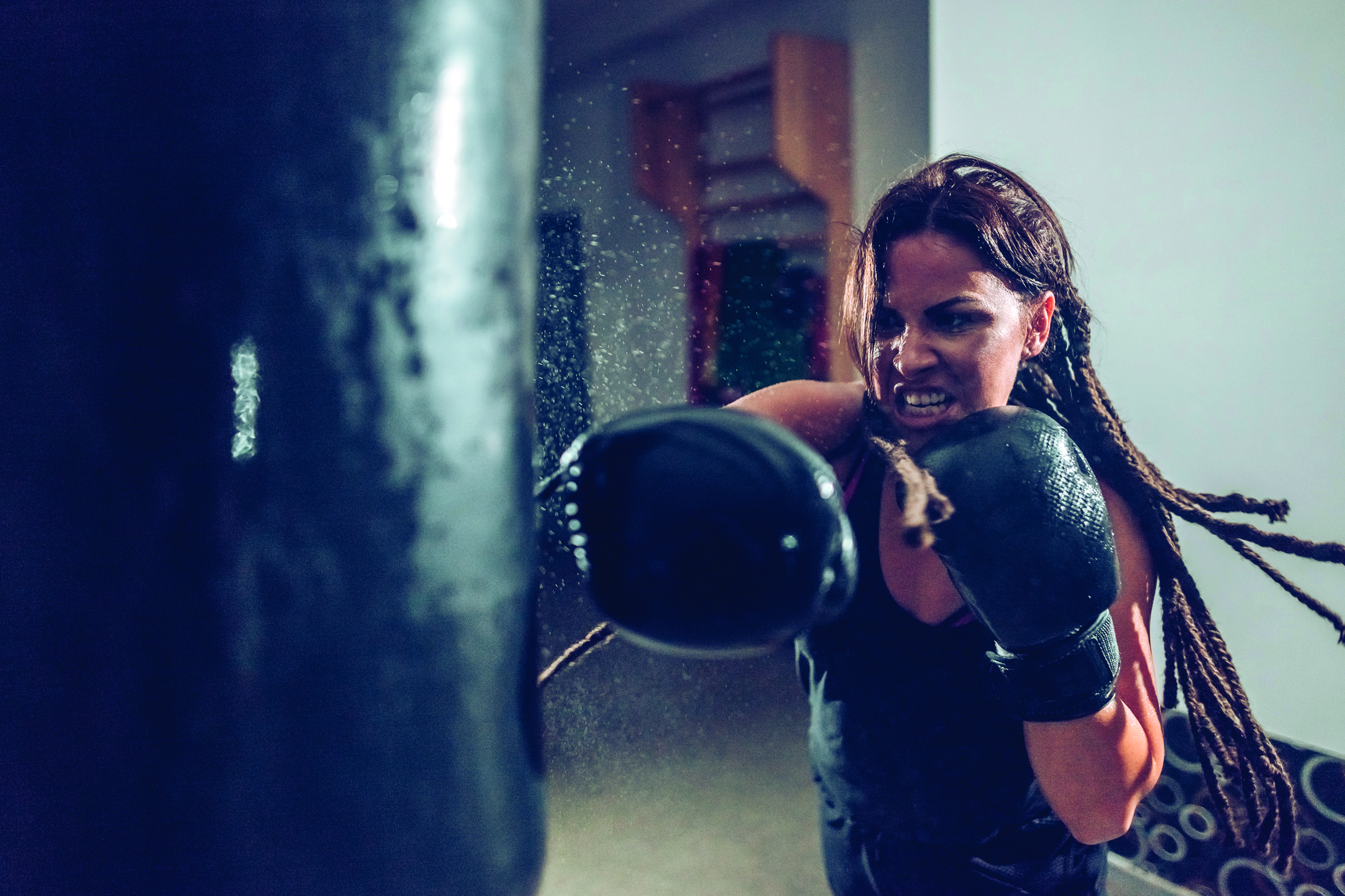 A woman wearing a black sweatshirt and black boxing gloves.
