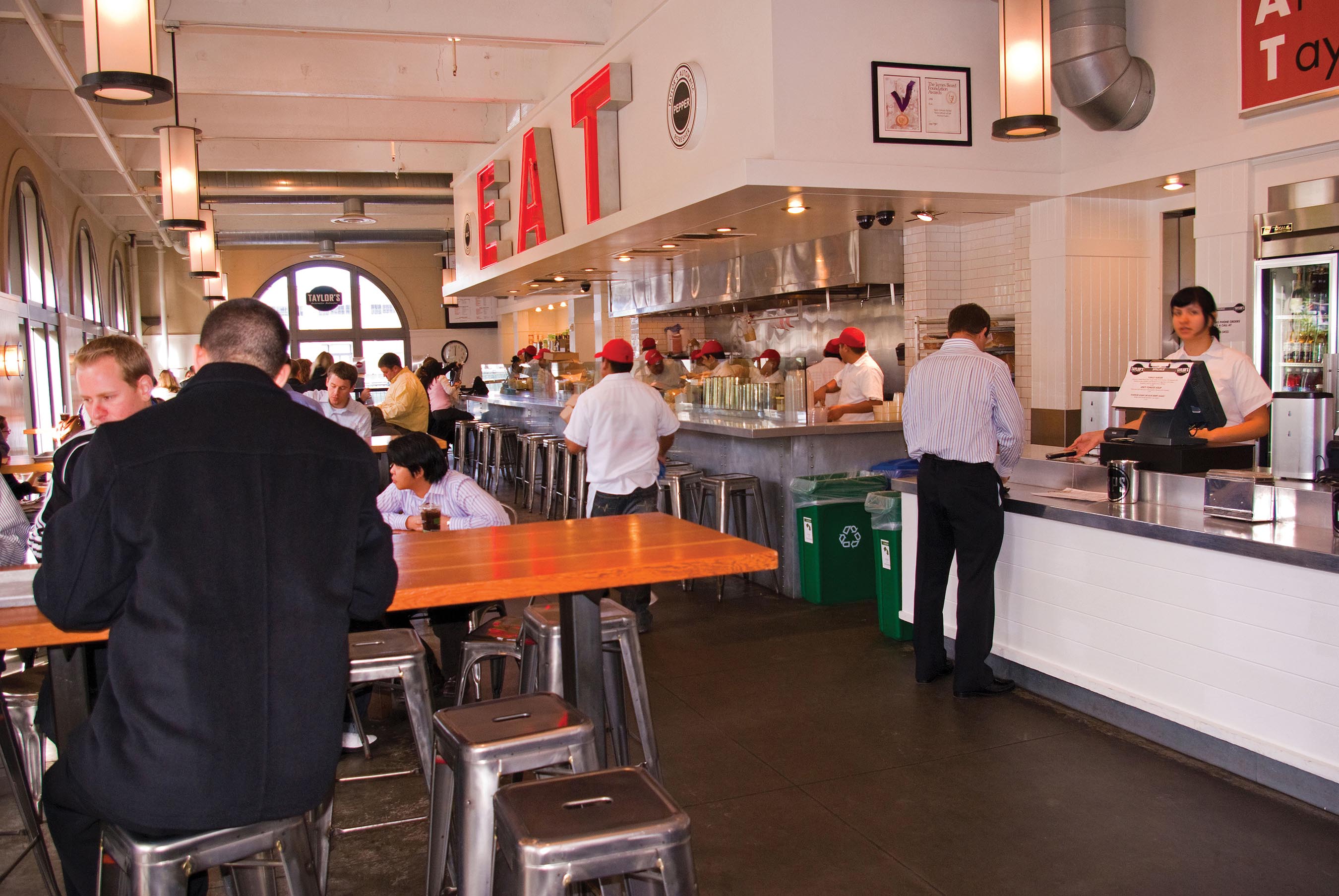 A fast food restaurant where people are having food on bar counters and shared tables along the wall.