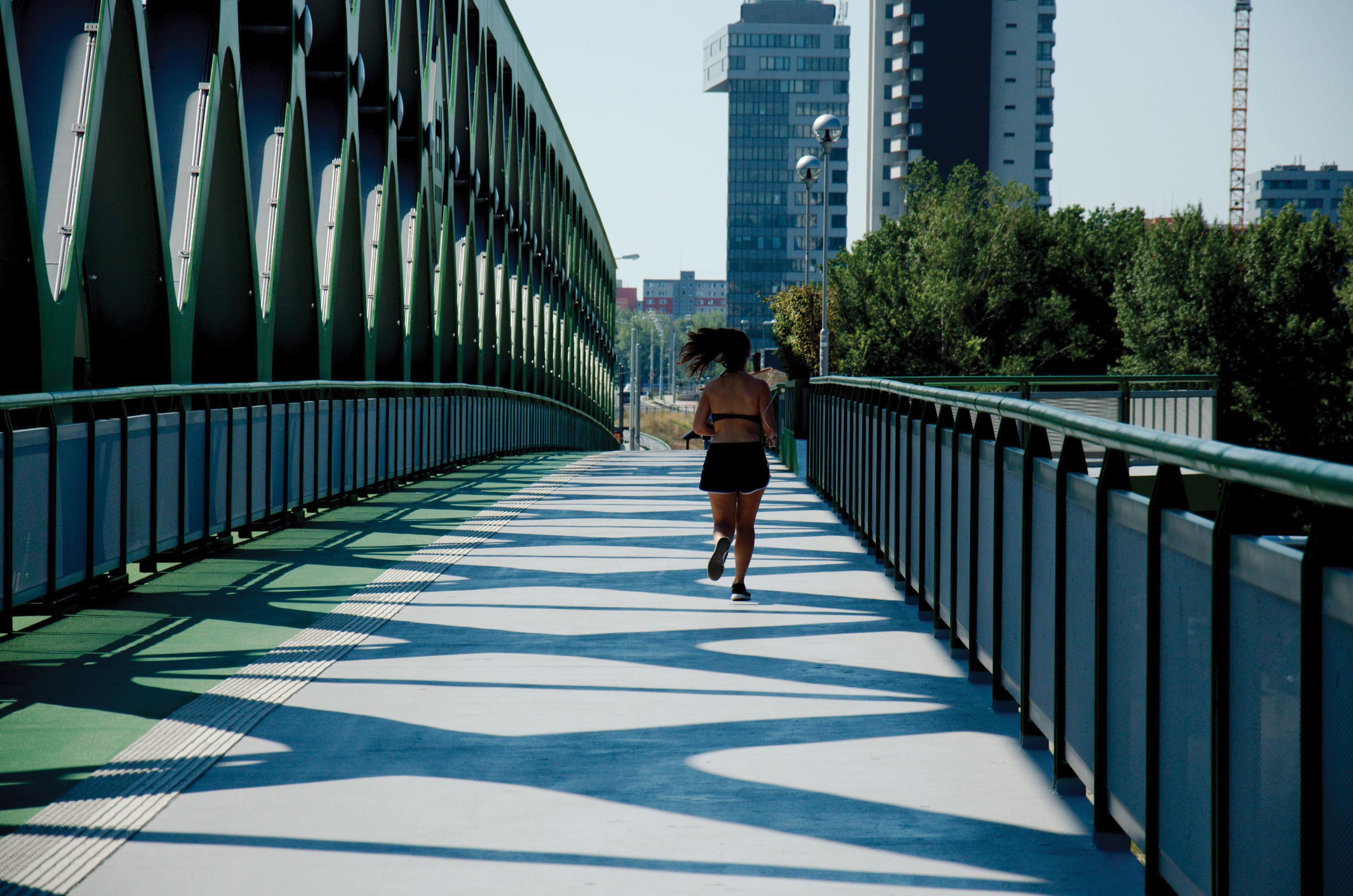 A woman jogs on a bridge alone.