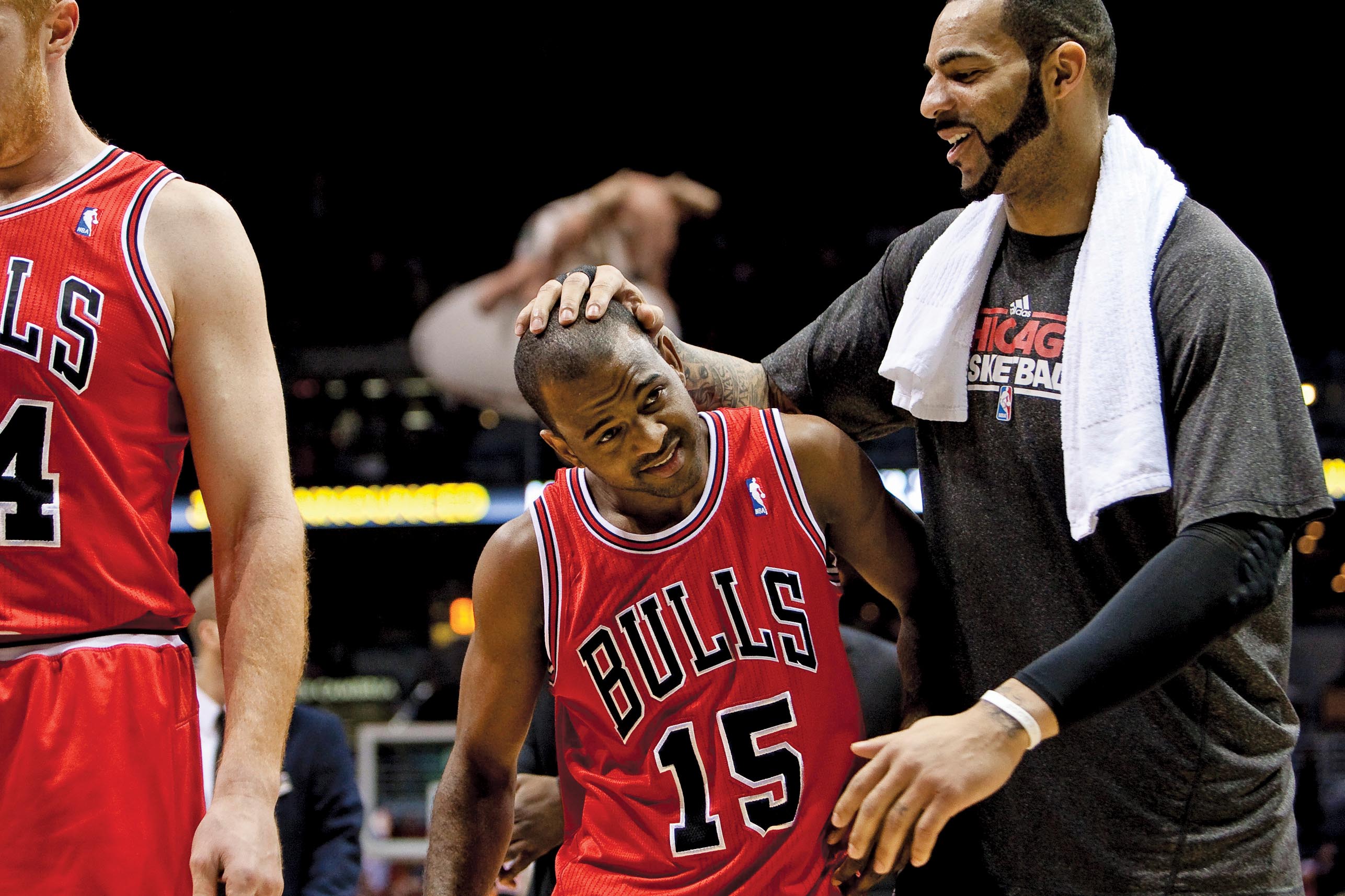 A taller basketball player stands and holds the head of John Lucas the third of the Chicago Bulls.