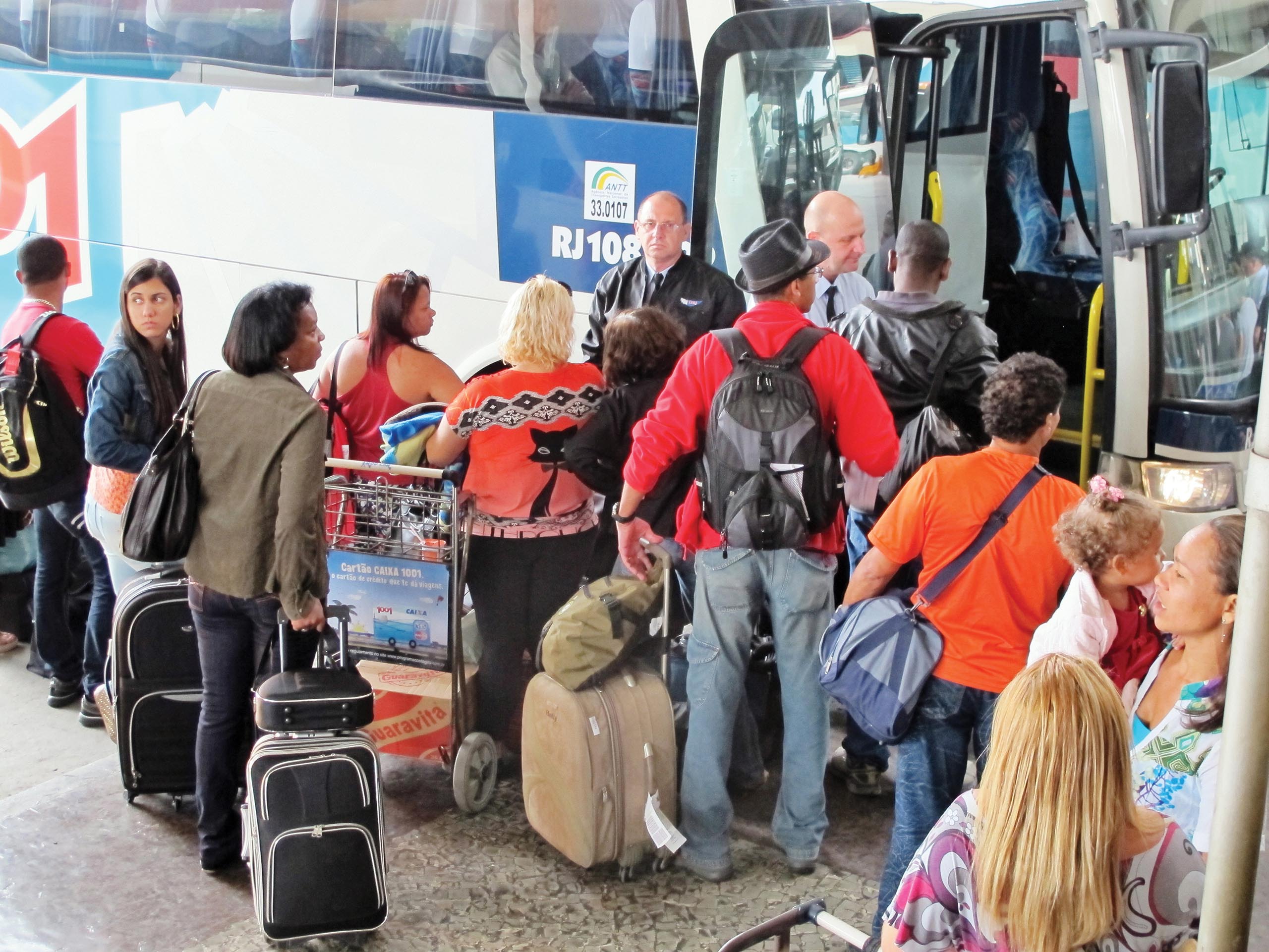 A photo shows people standing randomly while waiting outside the bus with their luggage in their hands.