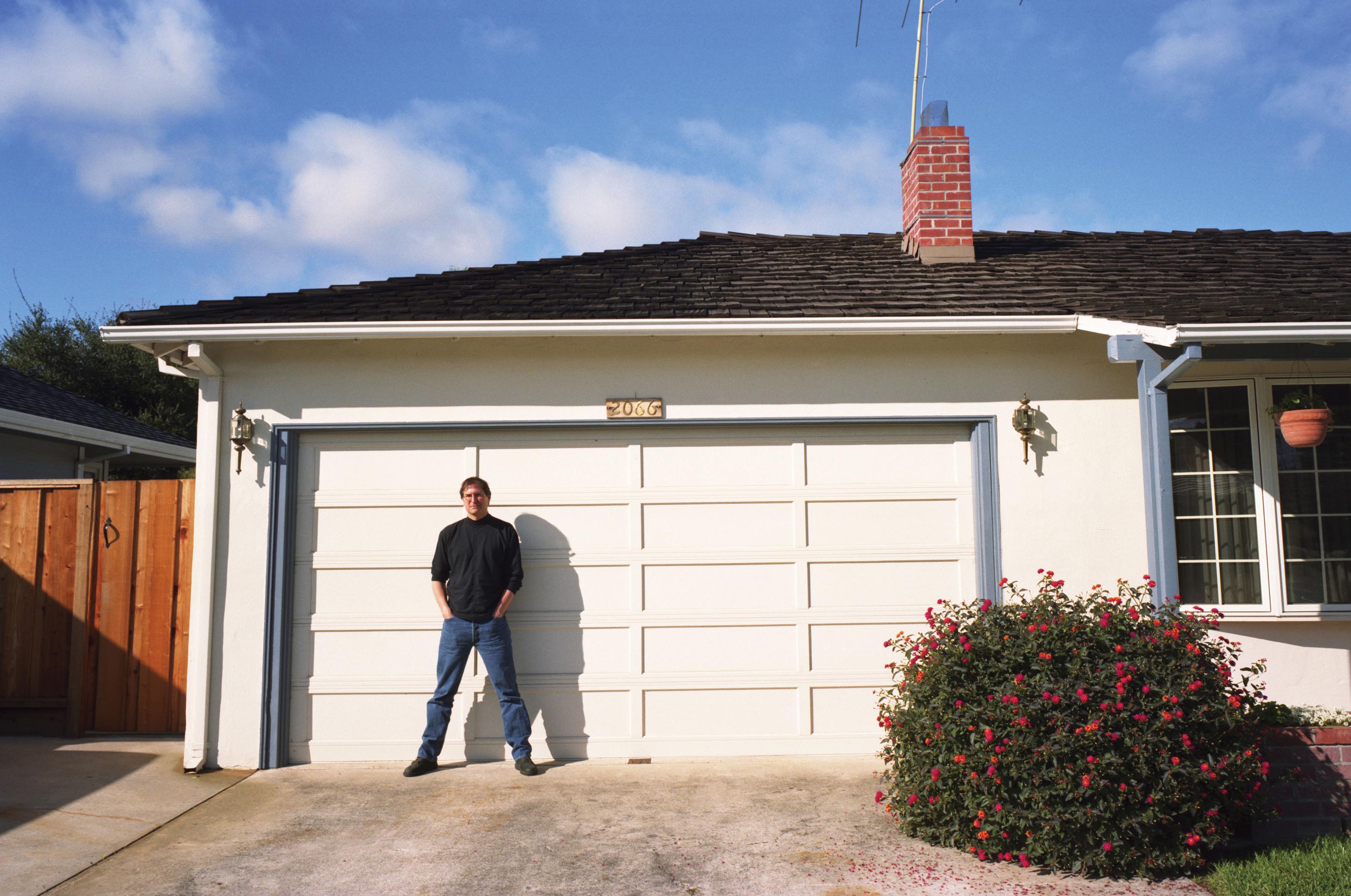 Steve Jobs standing outside a garage.