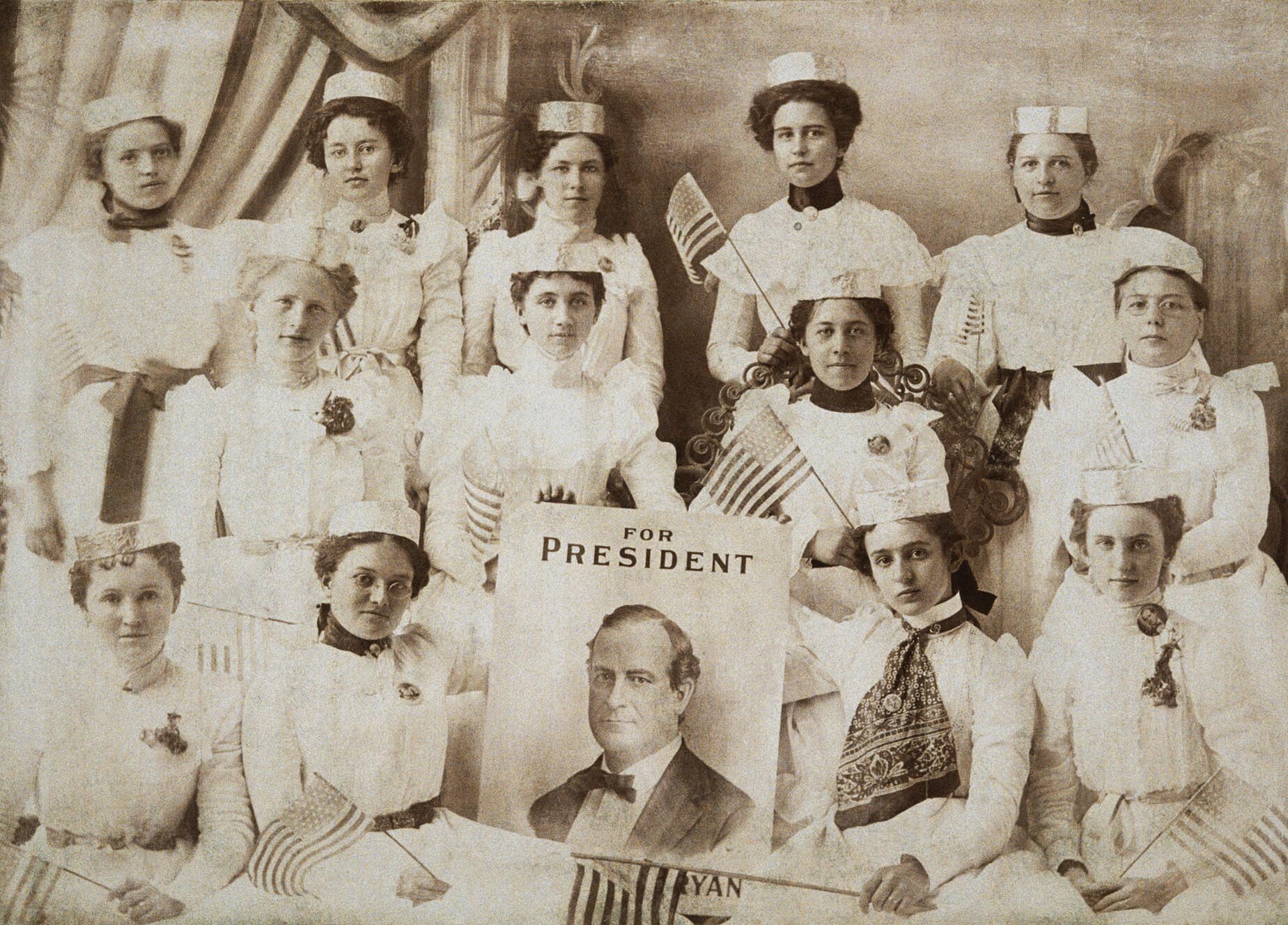 Thirteen women pose with a poster portrait of William Jennings Bryan.