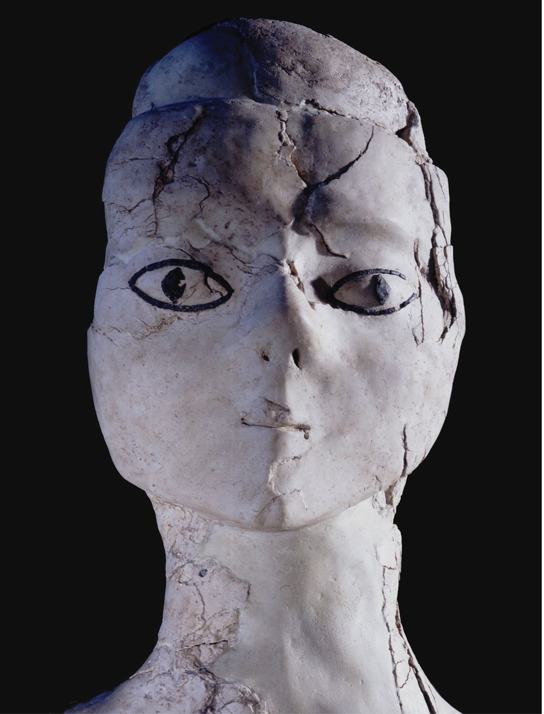 A stone statue featuring a human head and neck.