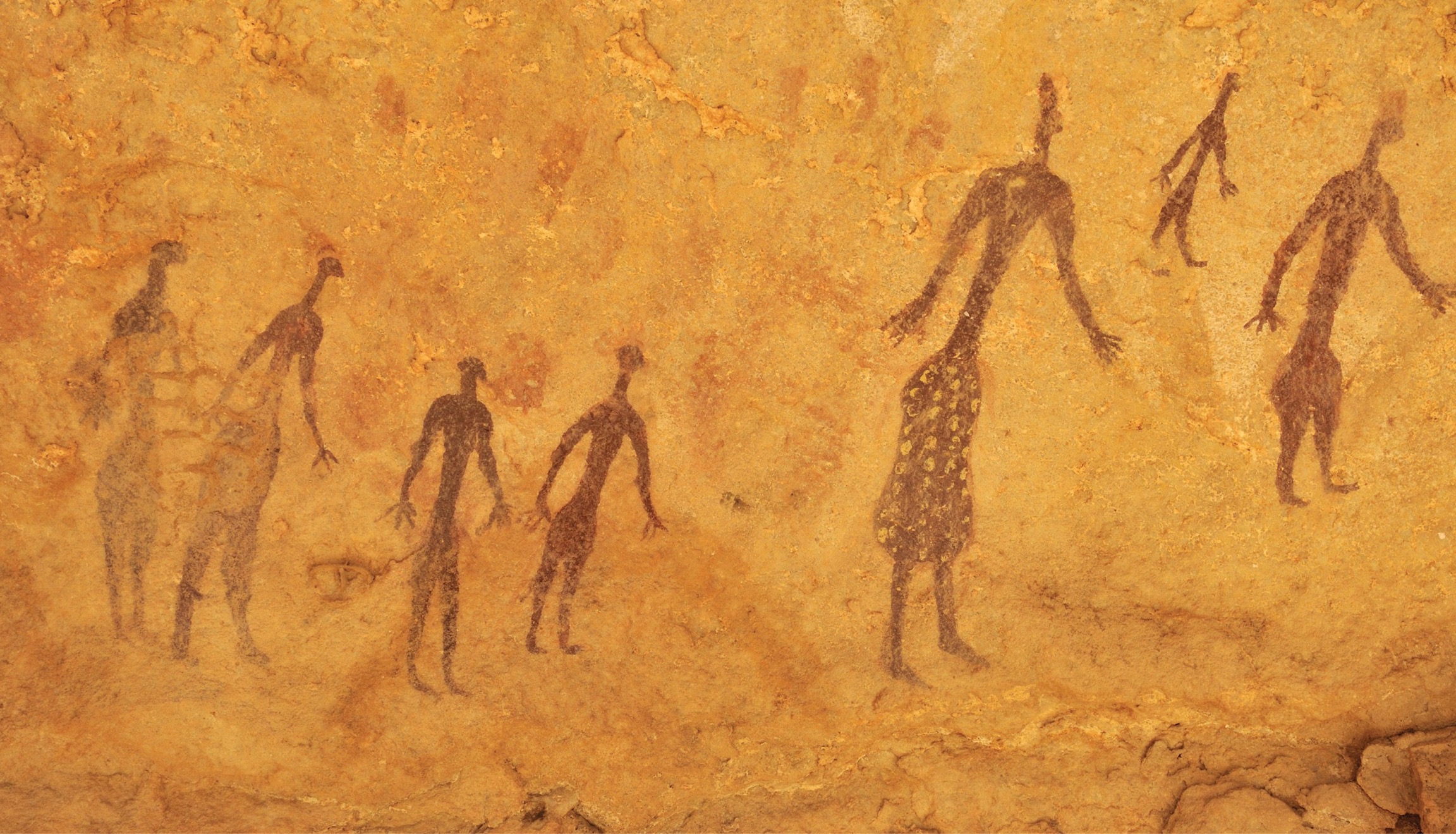 Paintings of seven human forms, each a different size, on a rock face in Algeria.