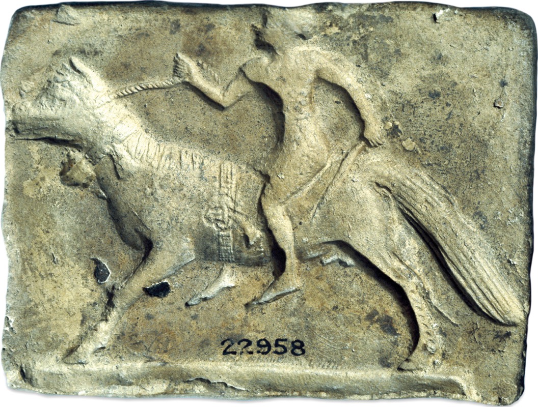 A Mesopotamian clay art shows a man riding a horse, holding a whip in one hand.