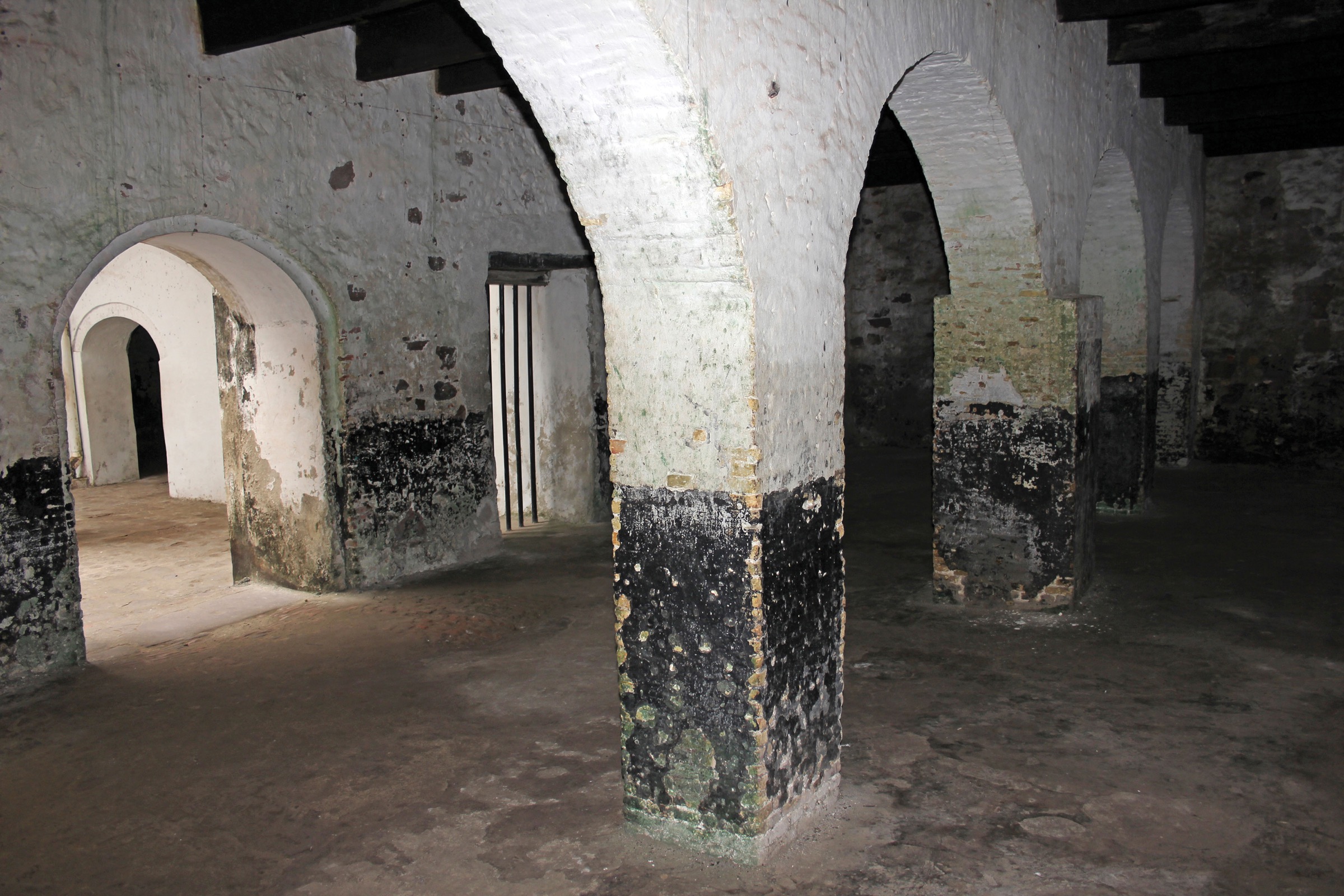 A photograph shows a musty basement with a colonnade and multiple archways.