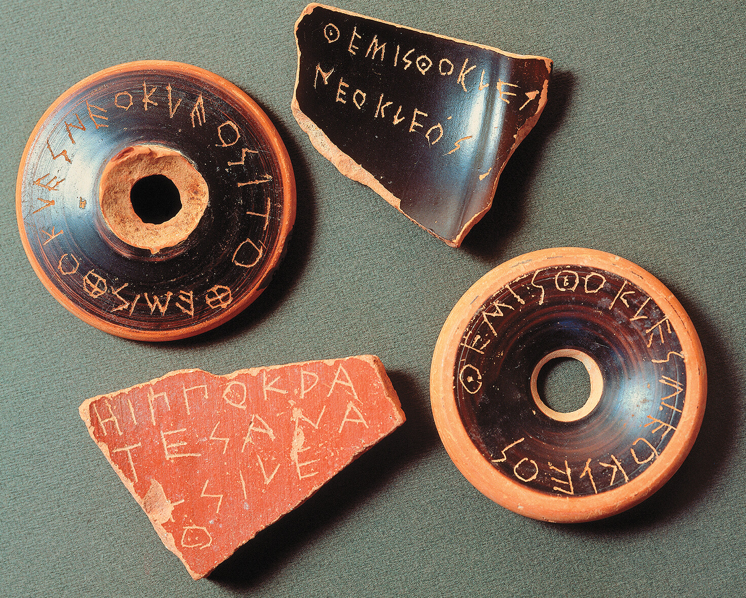 Four pieces of broken pottery with names etched into them.