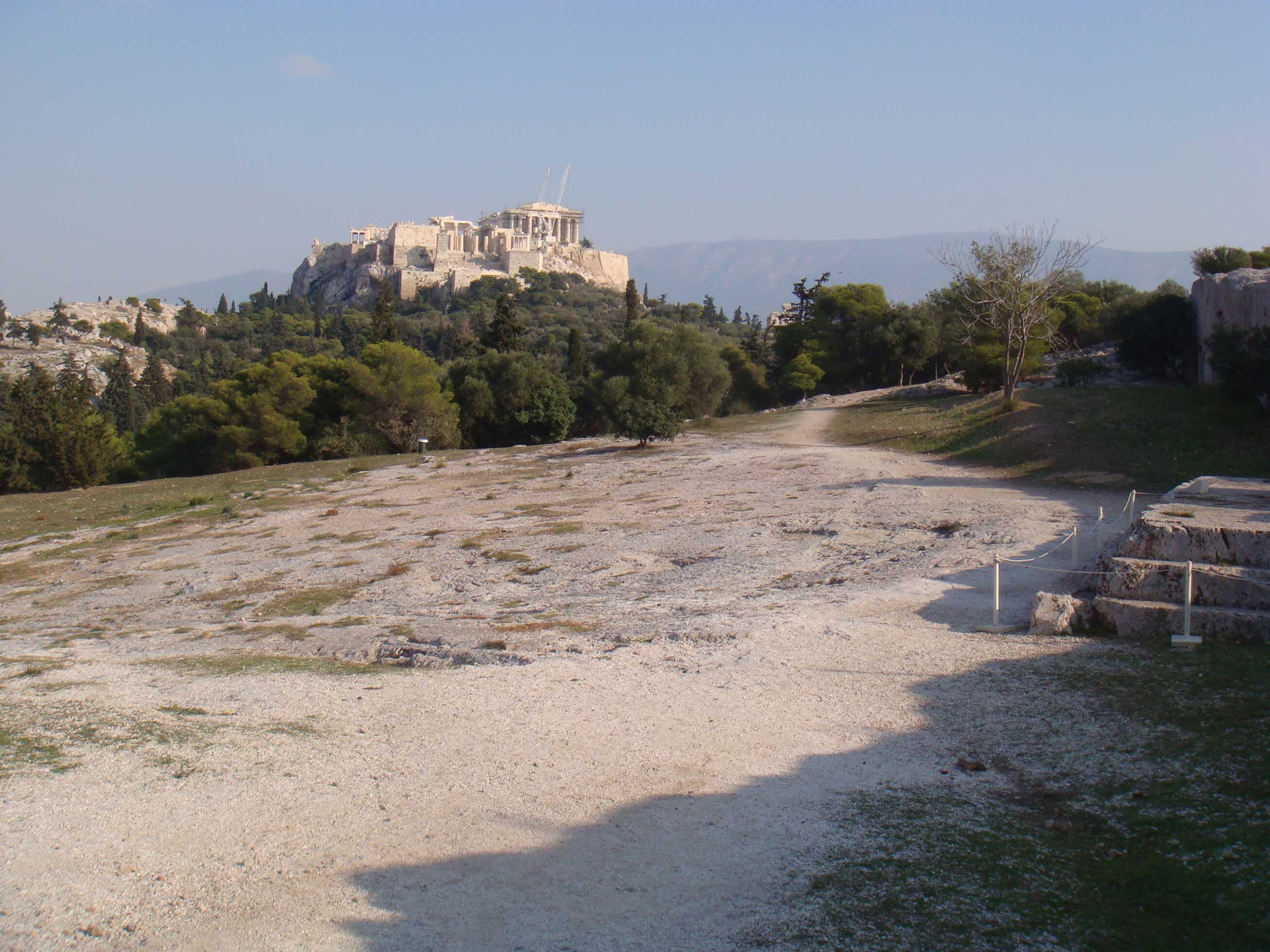 The Pnyx, a gently sloping hillside with sparse grass and white sand.