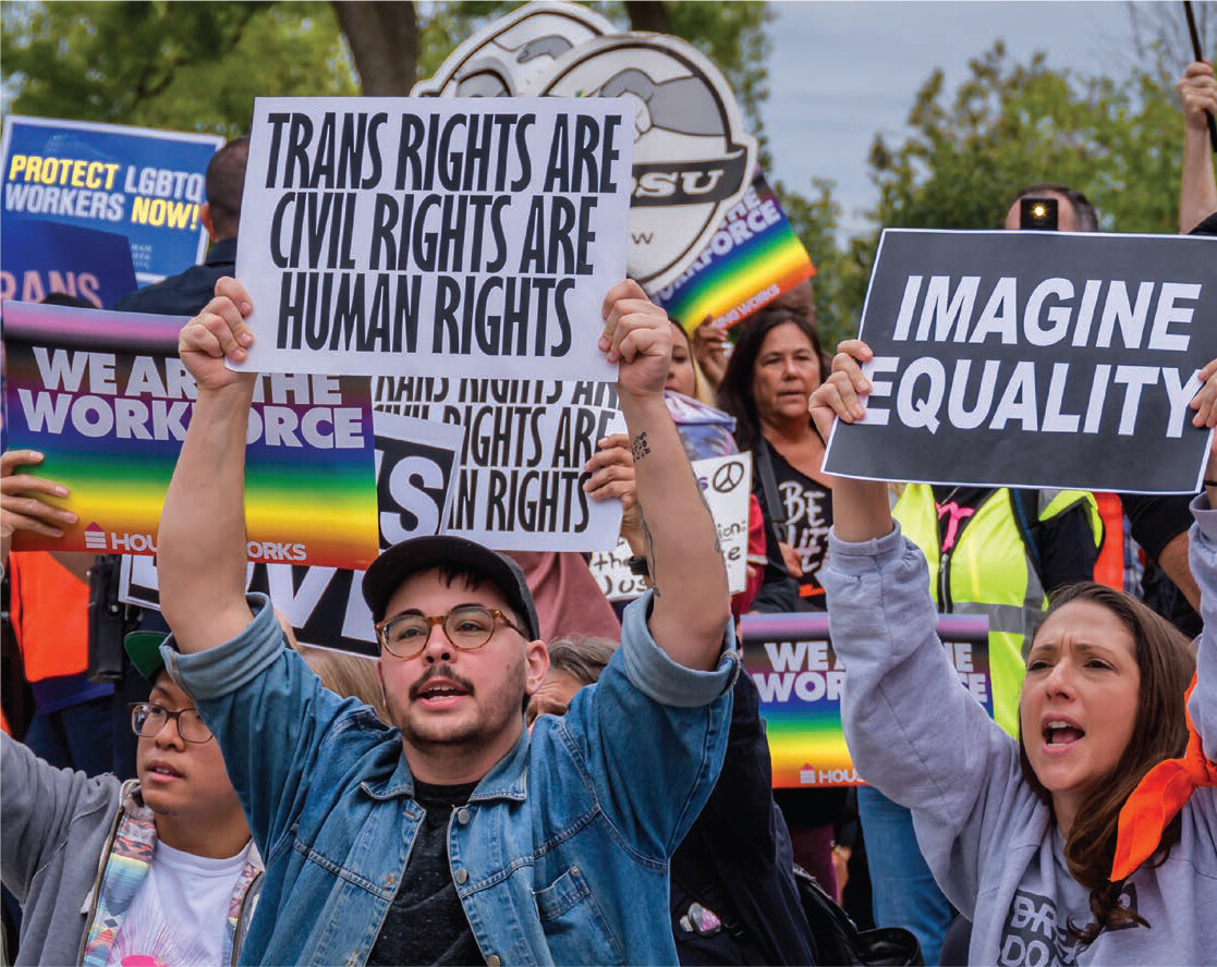 Marchers carry signs related to transgender rights.