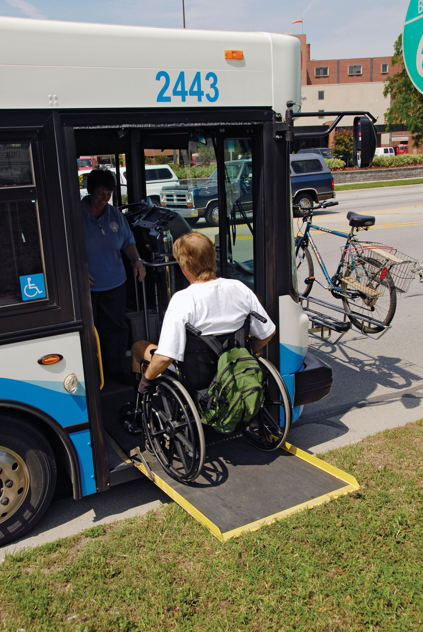 A person in a wheelchair rolling up onto a city bus.