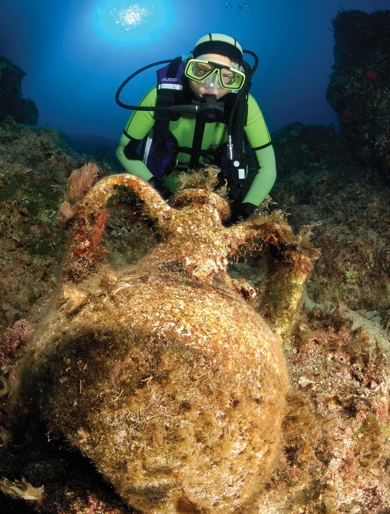 An underwater archaeologist scuba dives on top of a shipwreck.