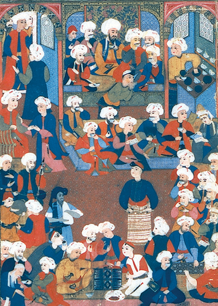Many people gathered together in a banquet hall while kneeling and standing around with coffee.