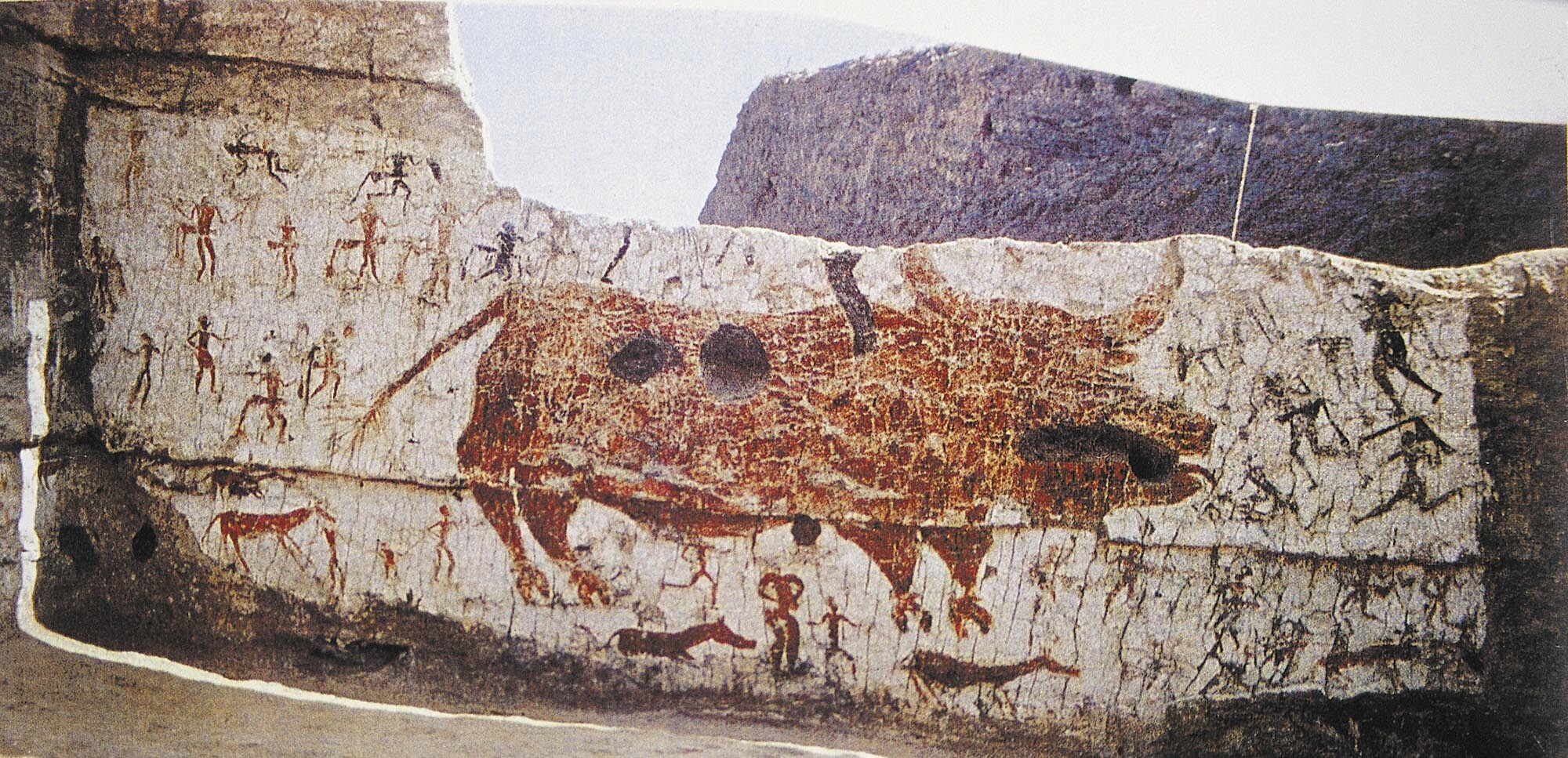 A painting on a rock wall depicts bull hunting by humans.