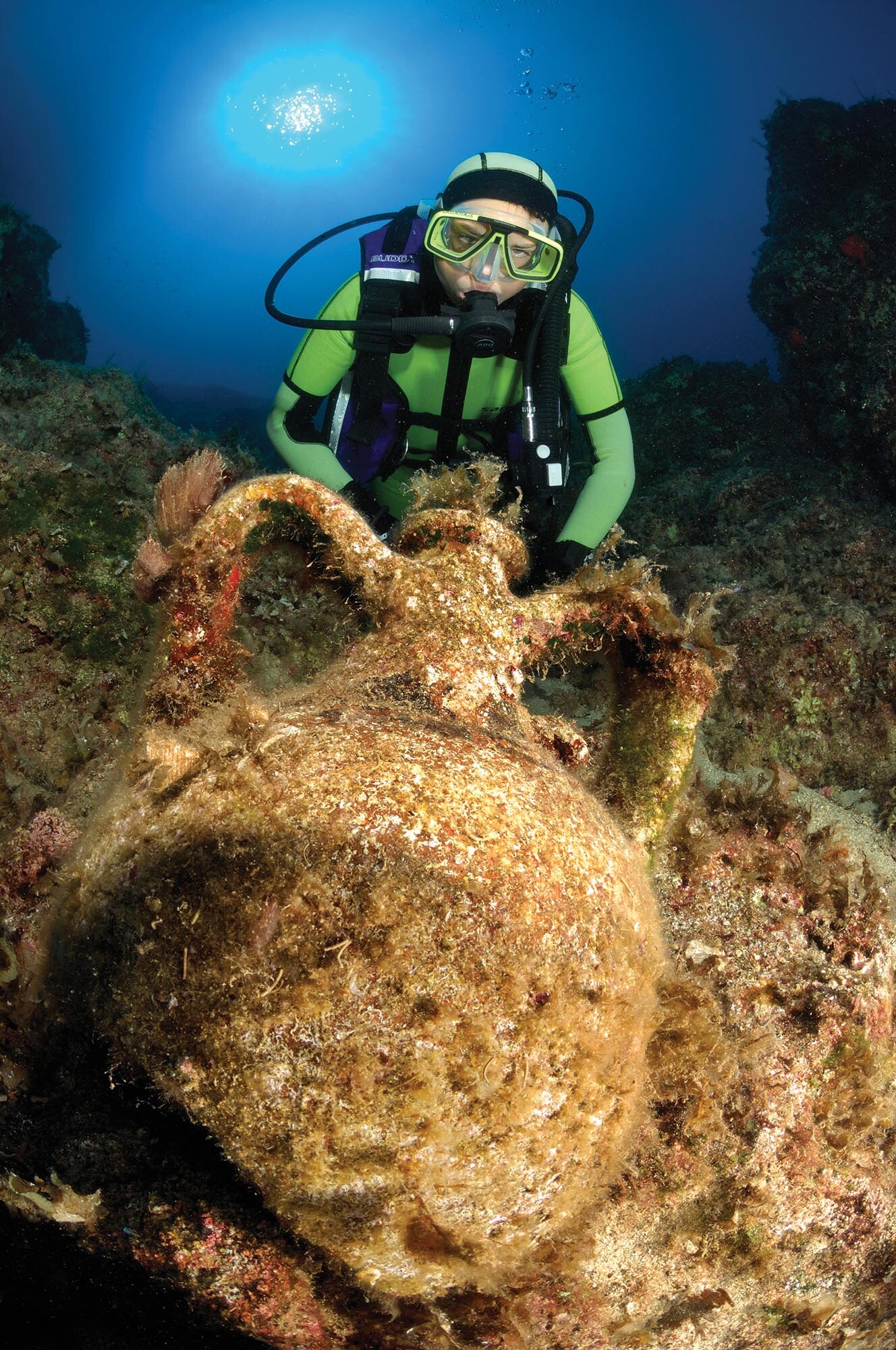 An underwater archaeologist scuba dives on top of a shipwreck.